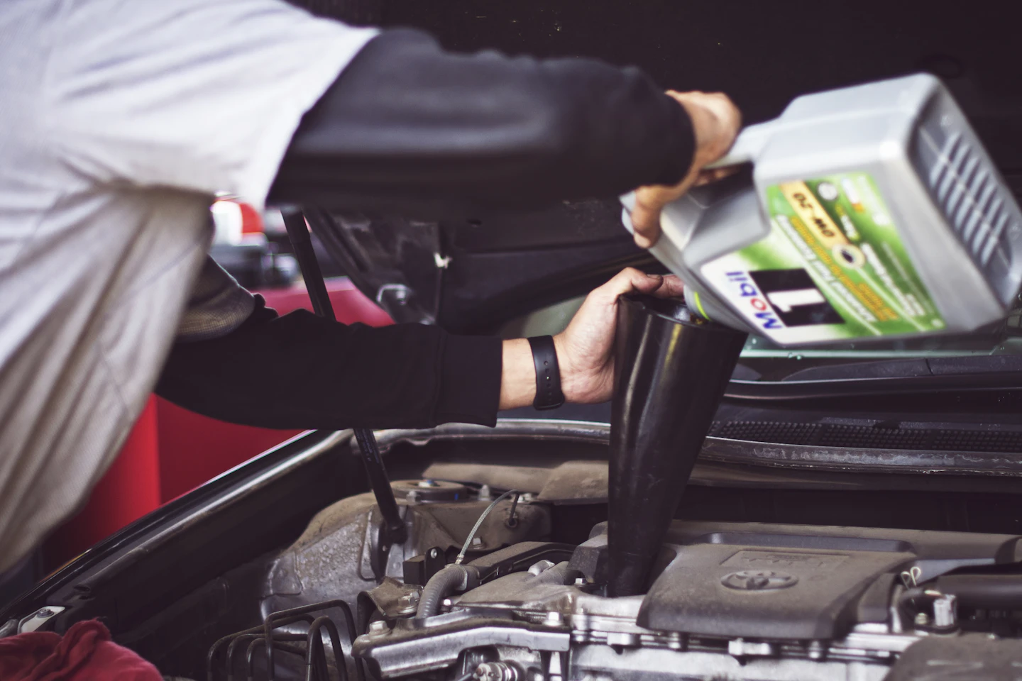 Technician adding motor oil to a vehicle during routine maintenance.
