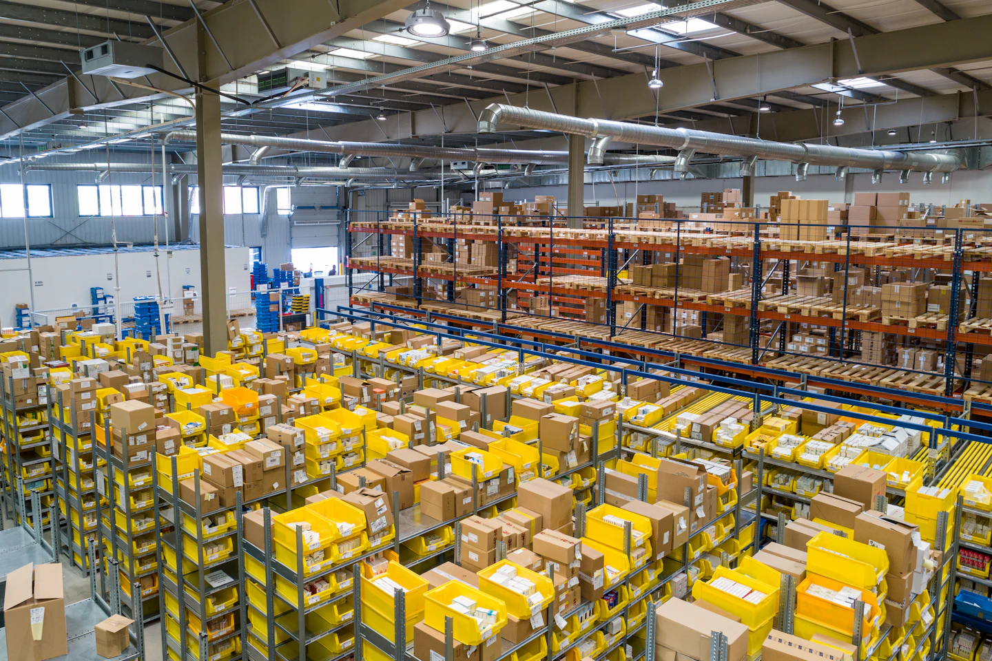 Warehouse inventory arranged in yellow picking bins and tall pallet racks.