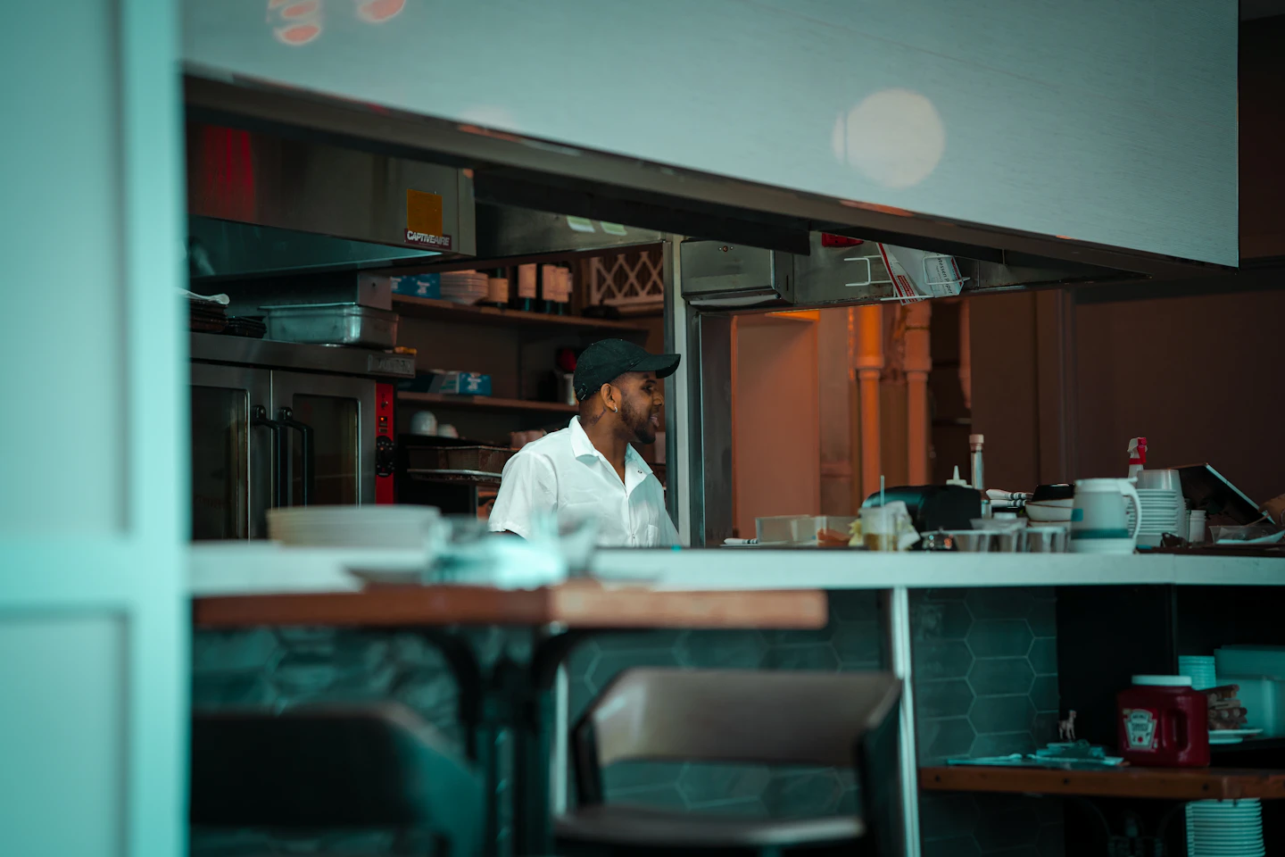 Chef working behind the service counter of a restaurant kitchen.