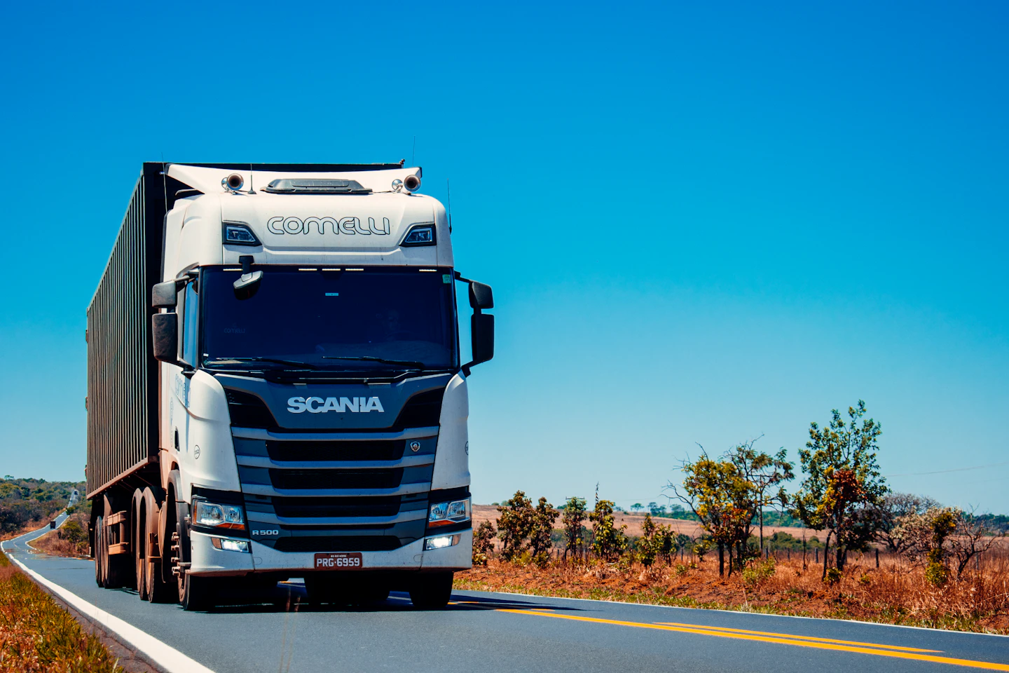 White freight truck traveling on a rural highway